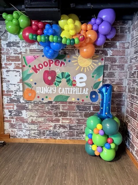 Rainbow garland with a twisted caterpillar and a number column for a first birthday