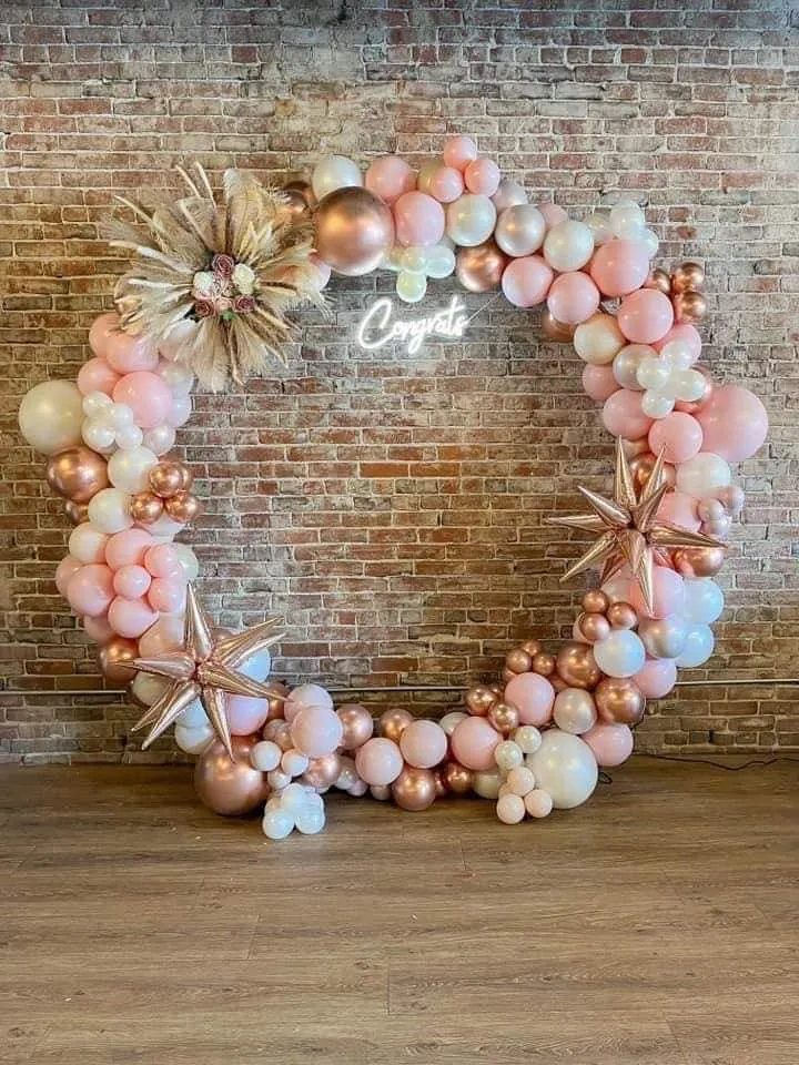 Blush, white and rose gold balloon hoop with a neon Congrats sign against a brick wall