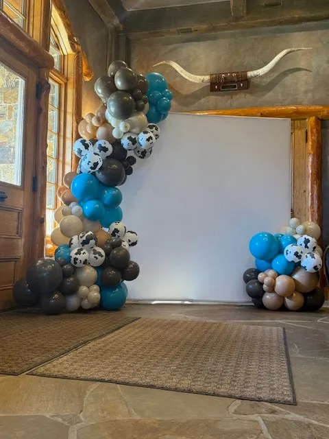 Organic garland in teal, brown and cow print framing a photo backdrop