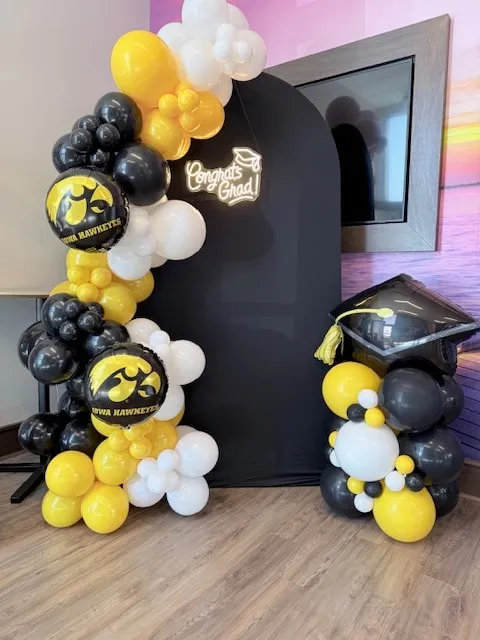 Graduation arch stand in black, gold and white with a grad cap column