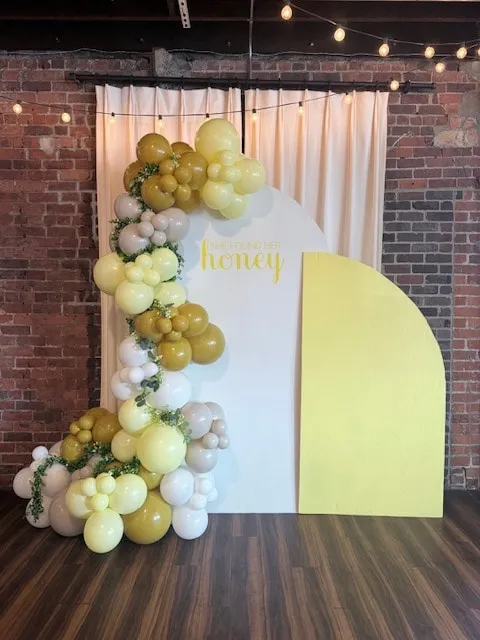 Arch backdrop with a butter, mustard and white garland and trailing greenery