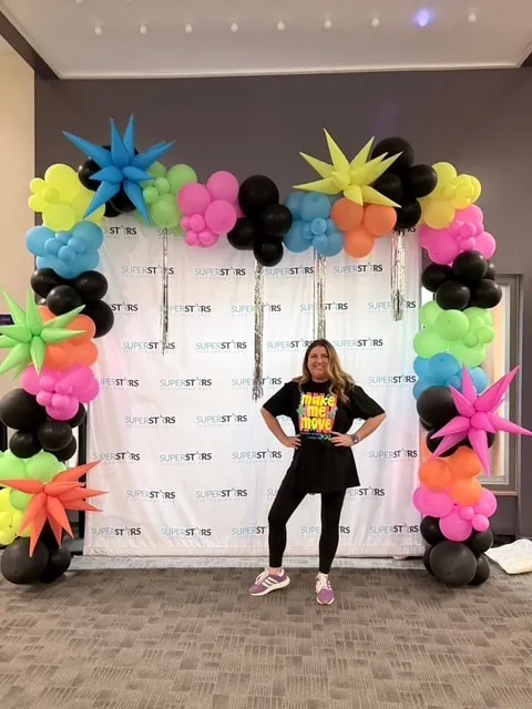 Neon organic arch with starbursts and fringe around a photo backdrop