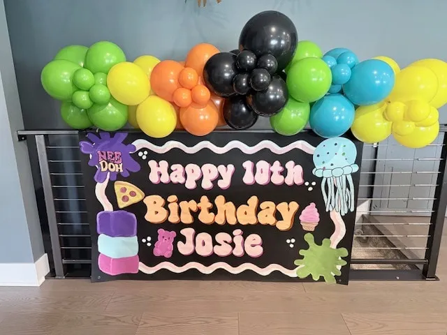 Bright garland in lime, orange, teal and black over a custom birthday banner
